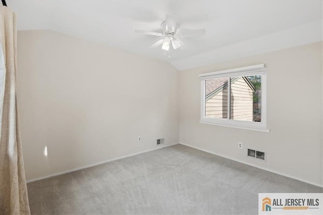 carpeted empty room with visible vents, baseboards, ceiling fan, and vaulted ceiling