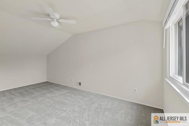 additional living space featuring carpet floors, a ceiling fan, vaulted ceiling, and visible vents