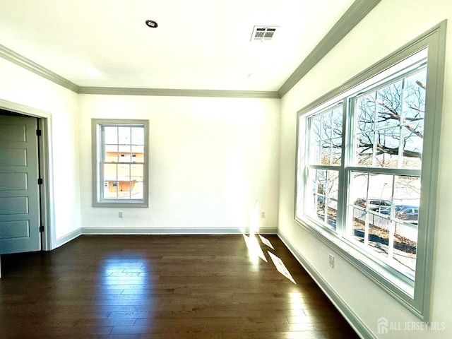empty room featuring baseboards, ornamental molding, dark wood-type flooring, and visible vents