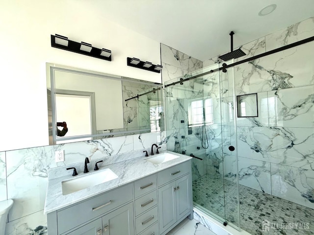 bathroom with tile walls, marble finish floor, a sink, and a marble finish shower