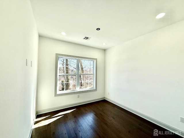 spare room featuring baseboards, visible vents, recessed lighting, and dark wood-style flooring