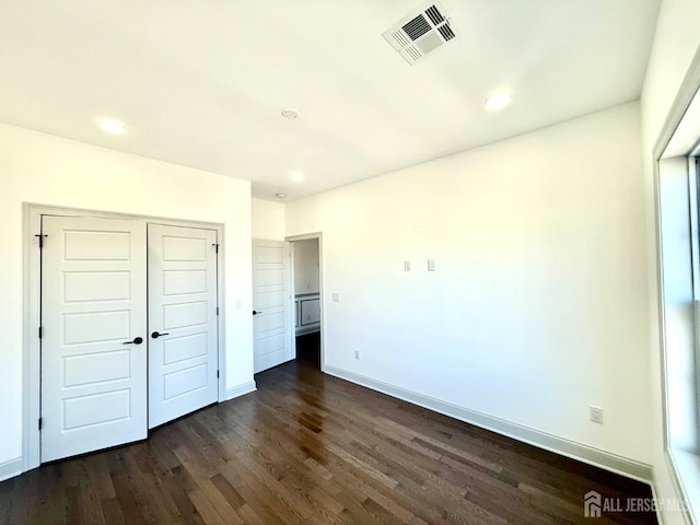unfurnished bedroom featuring dark wood-style floors, baseboards, visible vents, recessed lighting, and a closet