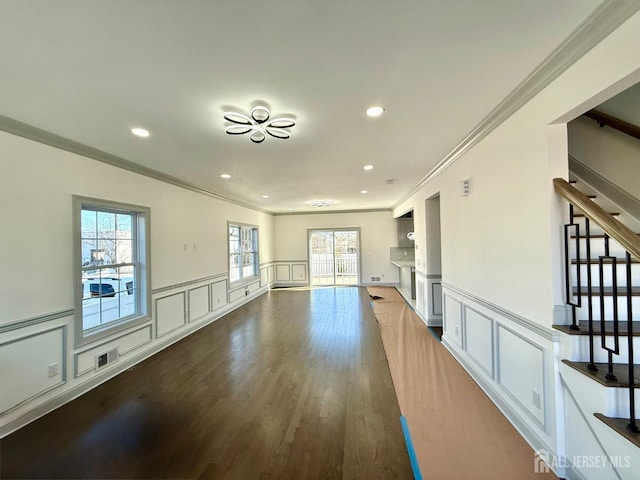 unfurnished living room featuring a decorative wall, stairway, visible vents, and ornamental molding