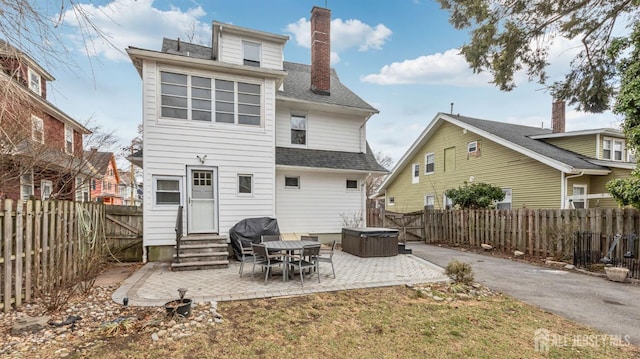 back of house with entry steps, a fenced backyard, a shingled roof, a chimney, and a patio area