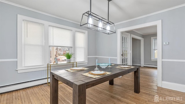 dining area with a baseboard heating unit, ornamental molding, wood finished floors, and baseboards