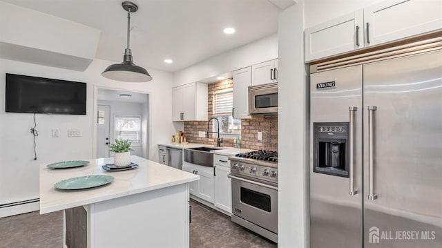 kitchen with tasteful backsplash, white cabinets, a baseboard radiator, high quality appliances, and a sink