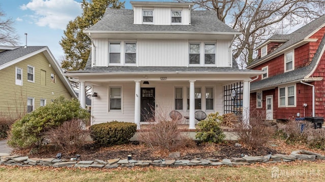 traditional style home featuring covered porch and roof with shingles