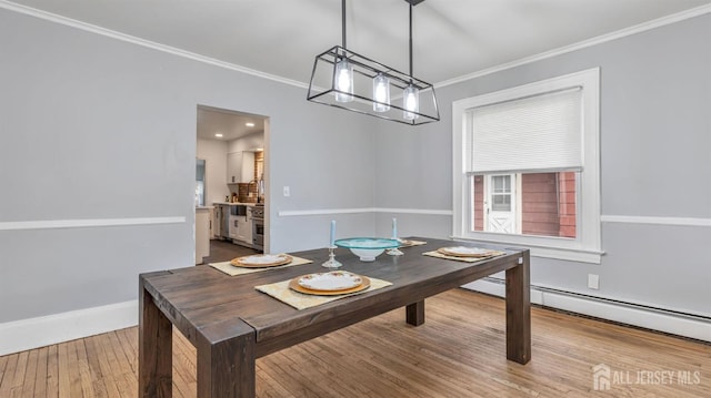 dining area featuring baseboards, a chandelier, crown molding, and wood finished floors