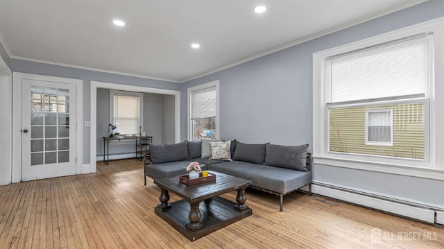 living room with a baseboard heating unit, a baseboard radiator, ornamental molding, and light wood-style flooring