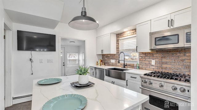 kitchen featuring stainless steel appliances, a healthy amount of sunlight, a baseboard heating unit, white cabinetry, and a sink