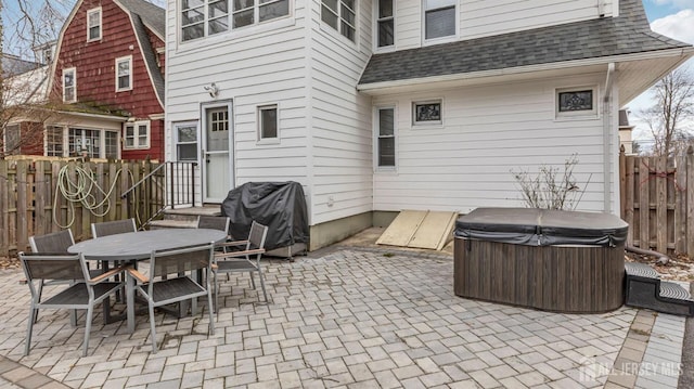 view of patio / terrace with a hot tub, outdoor dining area, a grill, and fence