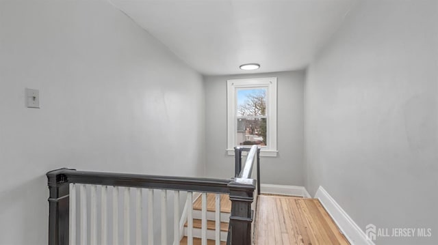 stairway with wood finished floors and baseboards