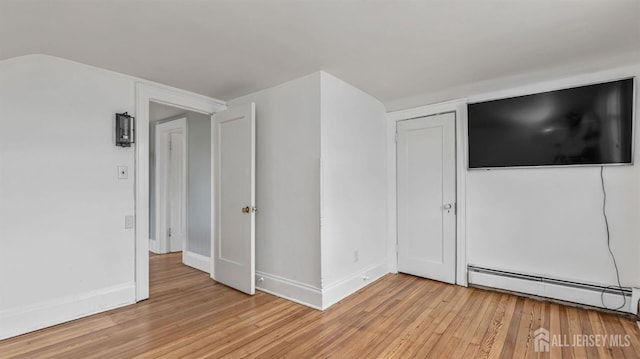 spare room with light wood-type flooring, baseboards, vaulted ceiling, and baseboard heating