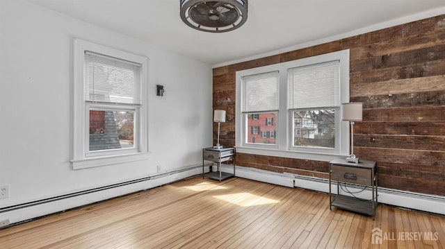 empty room with wooden walls, baseboard heating, and hardwood / wood-style flooring