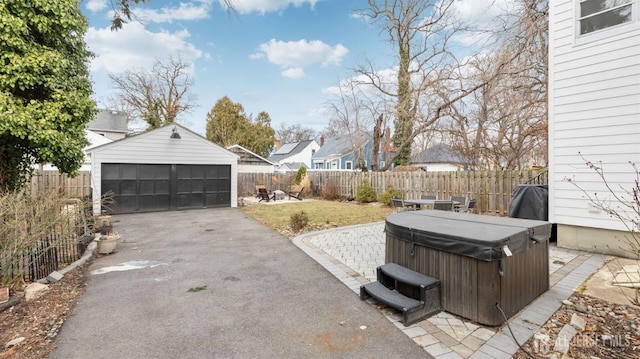 exterior space with a patio area, a hot tub, a fenced backyard, and an outbuilding