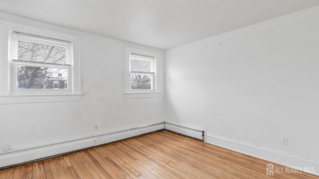 unfurnished room with baseboard heating and light wood finished floors