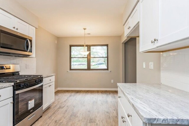 kitchen featuring tasteful backsplash, white cabinets, light wood-style flooring, appliances with stainless steel finishes, and light stone counters