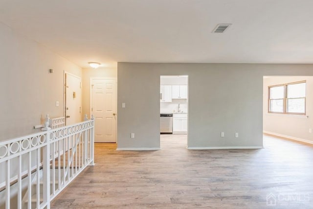 spare room featuring light wood-style floors, visible vents, and baseboards