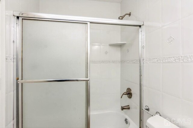 full bath featuring shower / bath combination with glass door and toilet