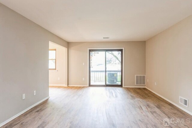 spare room featuring visible vents, baseboards, and wood finished floors