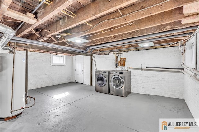 below grade area with water heater, brick wall, and independent washer and dryer