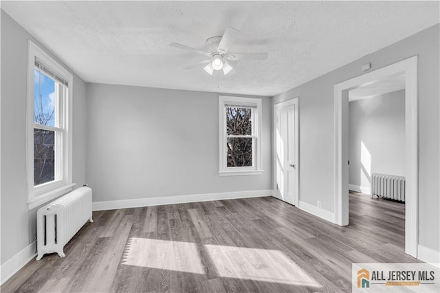 interior space featuring radiator, a ceiling fan, a textured ceiling, and wood finished floors