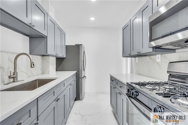 kitchen with light stone counters, marble finish floor, stainless steel appliances, decorative backsplash, and a sink