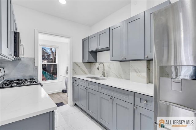 kitchen featuring light countertops, stainless steel appliances, gray cabinets, and a sink