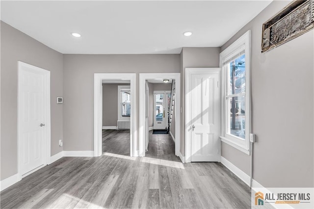 unfurnished bedroom with recessed lighting, baseboards, wood finished floors, and radiator