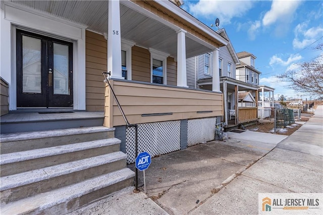 entrance to property with a porch and french doors