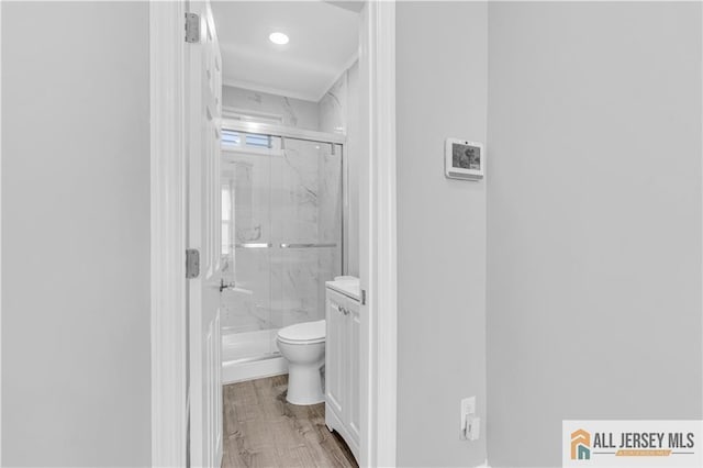 bathroom with toilet, a marble finish shower, and wood finished floors