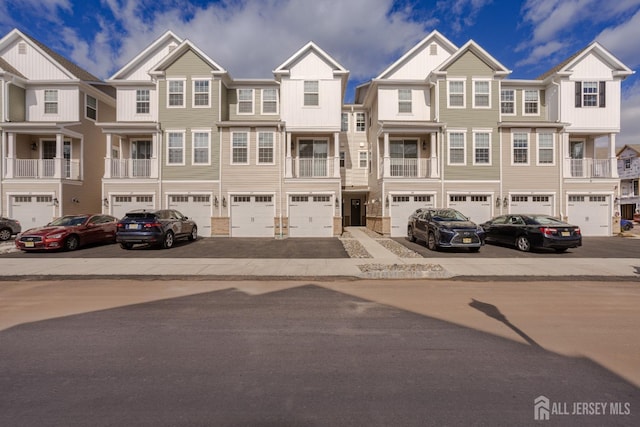 multi unit property featuring board and batten siding, a residential view, driveway, and an attached garage