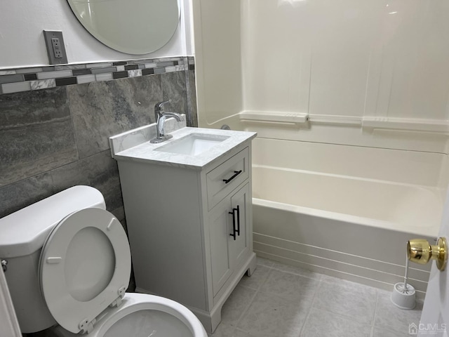 bathroom featuring toilet, tile patterned flooring, vanity, tile walls, and shower / bathing tub combination