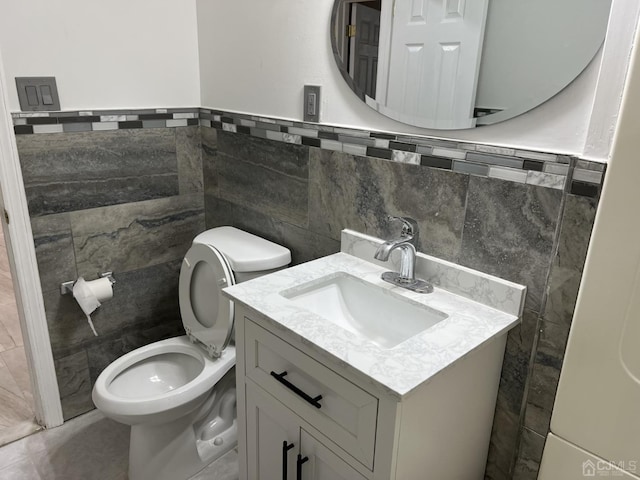 half bath with tile walls, vanity, and toilet