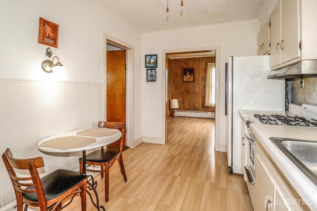 1107 River Rd, Piscataway, NJ 08854 - kitchen featuring a baseboard heating unit, under cabinet range hood, light wood finished floors, ornamental molding, and stainless steel range with gas stovetop