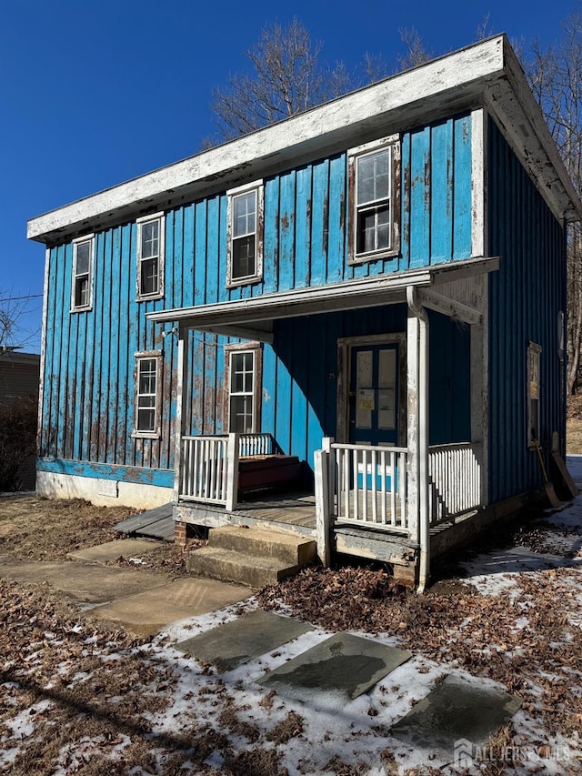 view of front of property with board and batten siding, covered porch, and french doors