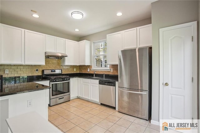 1115 Joseph Ct, South Plainfield, NJ 07080 - kitchen featuring appliances with stainless steel finishes, under cabinet range hood, dark countertops, white cabinetry, and light tile patterned flooring
