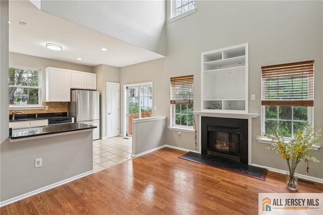 1115 Joseph Ct, South Plainfield, NJ 07080 - kitchen with dark countertops, freestanding refrigerator, white cabinets, a glass covered fireplace, and plenty of natural light