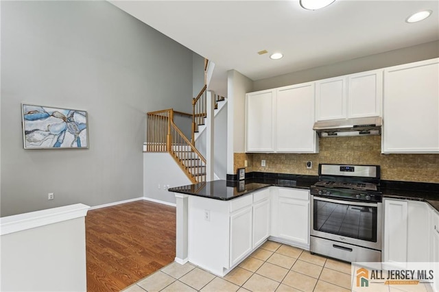 1115 Joseph Ct, South Plainfield, NJ 07080 - kitchen featuring stainless steel range with gas stovetop, ventilation hood, white cabinets, a peninsula, and decorative backsplash