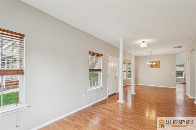 1115 Joseph Ct, South Plainfield, NJ 07080 - empty room with ornate columns, a chandelier, plenty of natural light, and light wood-style flooring