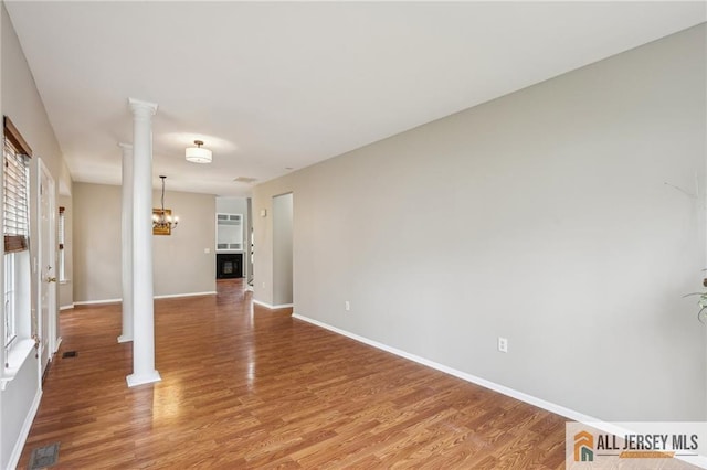 1115 Joseph Ct, South Plainfield, NJ 07080 - unfurnished room with ornate columns, light wood-style floors, baseboards, and a chandelier