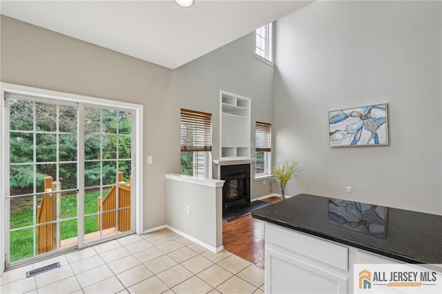 1115 Joseph Ct, South Plainfield, NJ 07080 - kitchen with white cabinets, a glass covered fireplace, light tile patterned flooring, baseboards, and a high ceiling