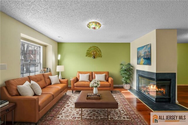 living room featuring dark wood-type flooring, a multi sided fireplace, and a textured ceiling