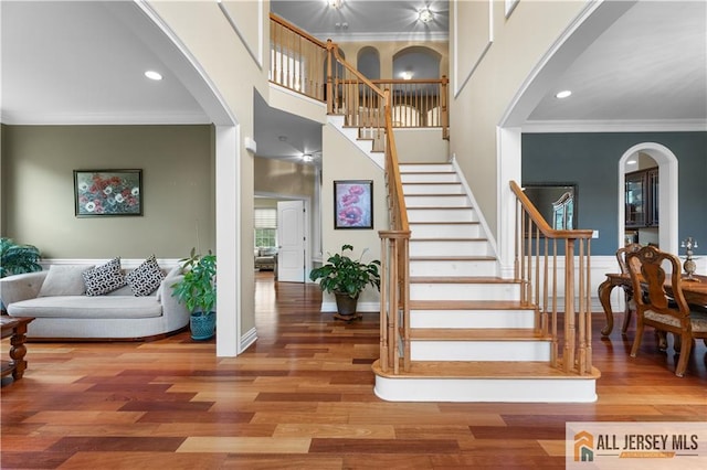 6 Monet Ct, South Brunswick, NJ 08852 - staircase featuring ornamental molding, wood finished floors, arched walkways, a high ceiling, and recessed lighting