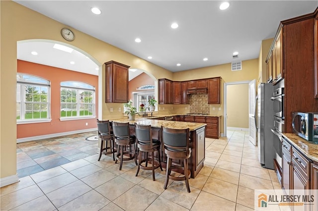 6 Monet Ct, South Brunswick, NJ 08852 - kitchen featuring appliances with stainless steel finishes, a kitchen breakfast bar, arched walkways, light stone counters, and recessed lighting