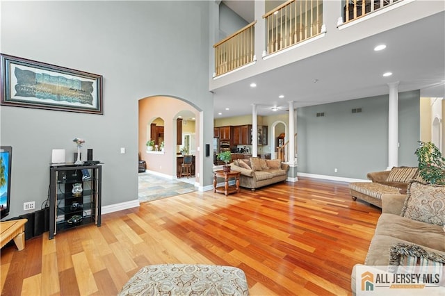 6 Monet Ct, South Brunswick, NJ 08852 - living room with arched walkways, light wood-style flooring, a towering ceiling, and ornate columns