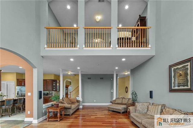 6 Monet Ct, South Brunswick, NJ 08852 - living area featuring light wood finished floors, arched walkways, a towering ceiling, recessed lighting, and stairs