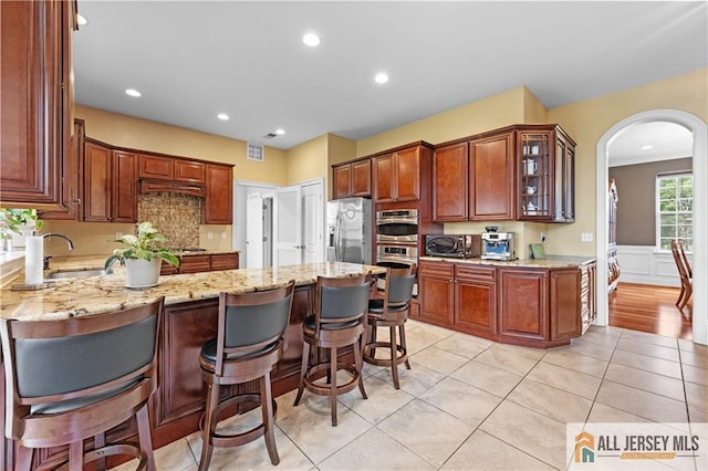 6 Monet Ct, South Brunswick, NJ 08852 - kitchen featuring appliances with stainless steel finishes, arched walkways, a peninsula, light stone countertops, and recessed lighting