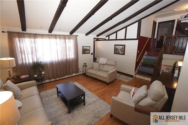 living area featuring lofted ceiling with beams, stairway, and wood finished floors