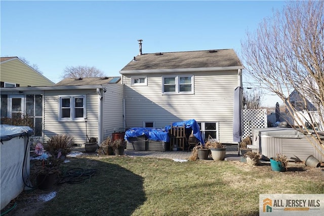 back of house featuring a yard and a hot tub